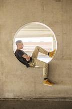 a teenage boy sitting in a circular window 