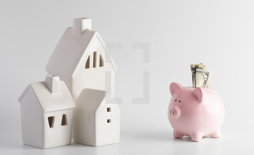 piggy bank and small white houses against a white background 