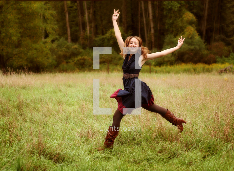 a joyful woman dancing in a field 