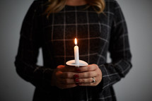 a woman holding a single candle 
