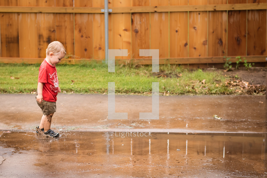 a toddler boy splashing in puddles 