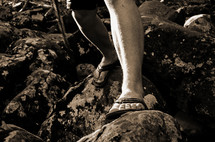 feet in flip flops standing on rocks 