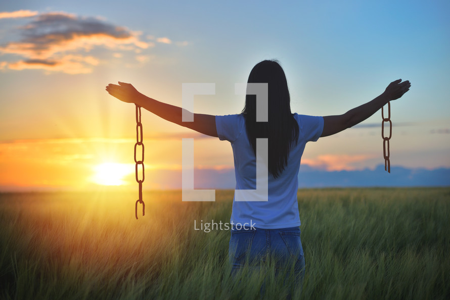 Woman feeling free in a beautiful natural setting, in what field at sunset. Free from chains
