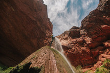 misting waterfall and red rock cliffs 