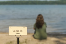 word vacation on a sign beside of a lake 