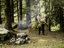 Man holding woman near campfire