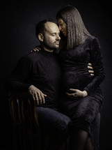 Man and pregnant woman sitting in chair for portrait