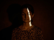 a sliver of light on a female model's face against a red background 