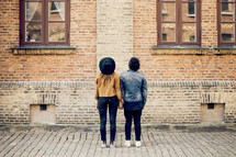 Couple holding hands standing in front of a brick building.