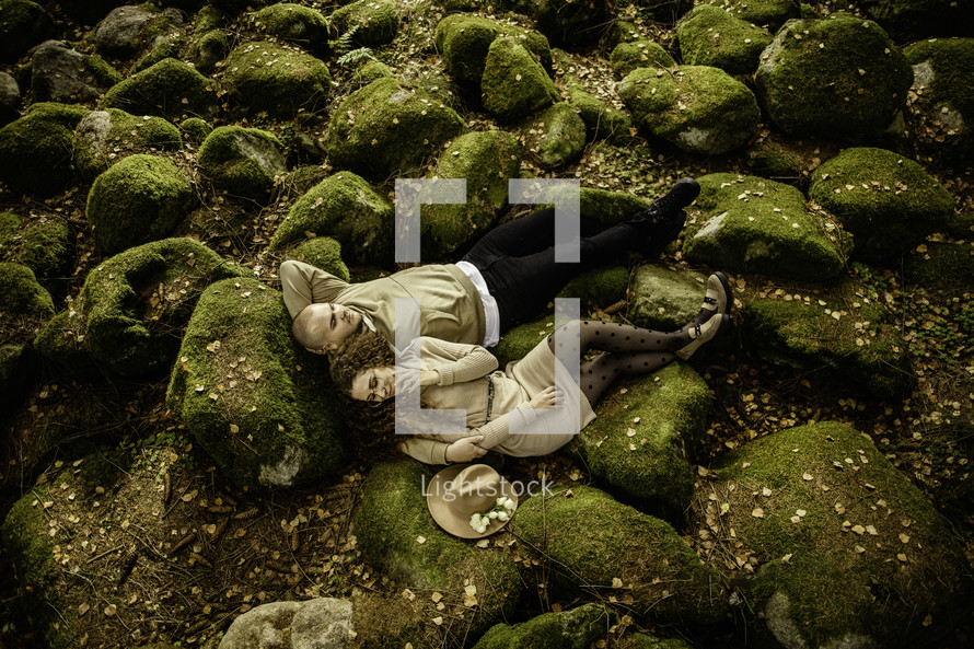 Couple laying down on moss covered rocks
