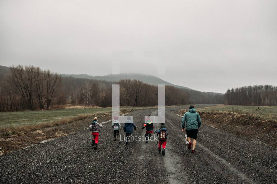 children and father running on a gravel road 