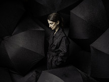 Woman in black raincoat in black umbrellas