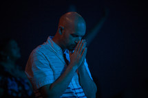 male with head bowed in prayer during a worship service 