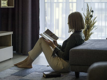 a woman sitting on the floor reading a Bible 
