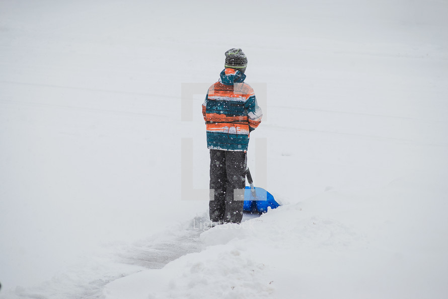 child digging with a shovel in snow 
