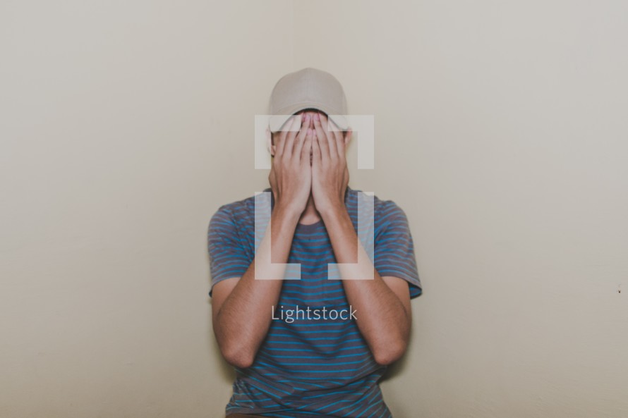 a man covering his face with his hands 