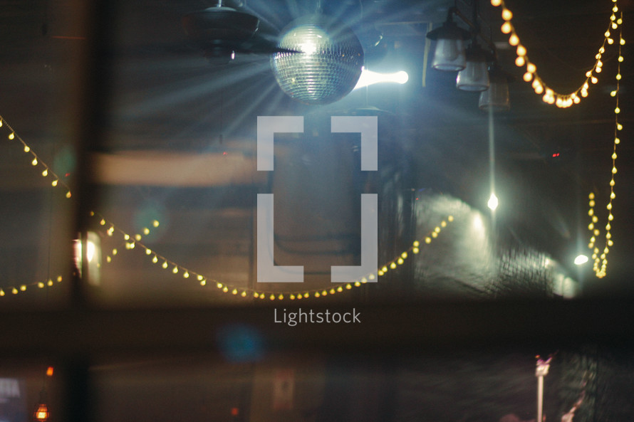 disco ball and strung lights over a dance floor 