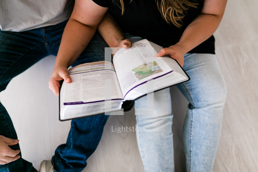 a husband and wife reading a Bible together 
