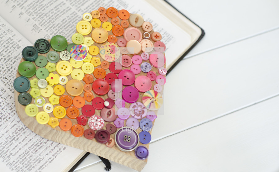 heart of buttons on the pages of a Bible 