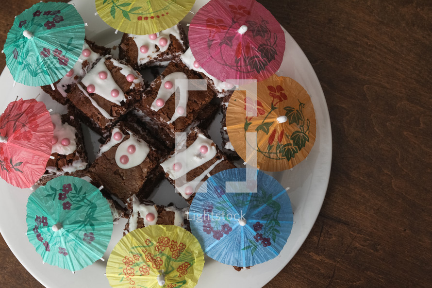 Child made platter of brownies with cocktail umbrellas 