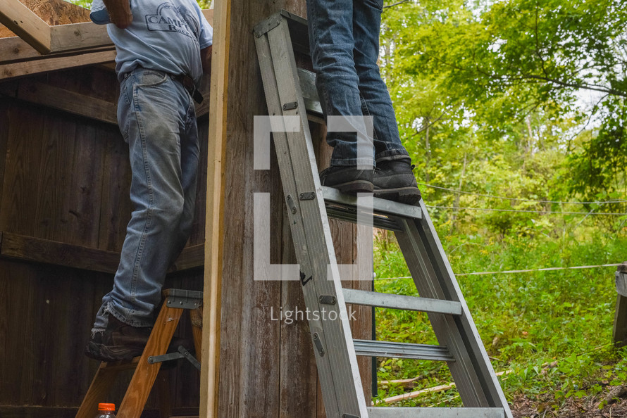 two men standing on ladders 