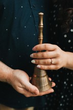 a couple holding a bell 