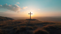 A cross on the top of a hill at sunset