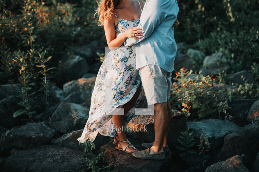 a couple standing on rocks embracing 