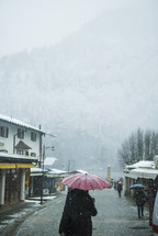 a woman walking carrying an umbrella in the snow 