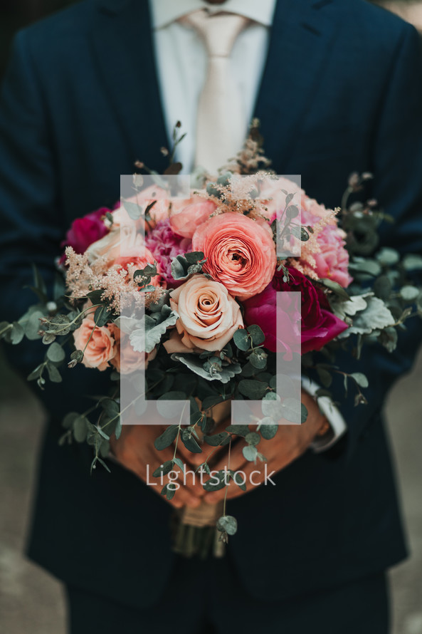 groom holding a bouquet 
