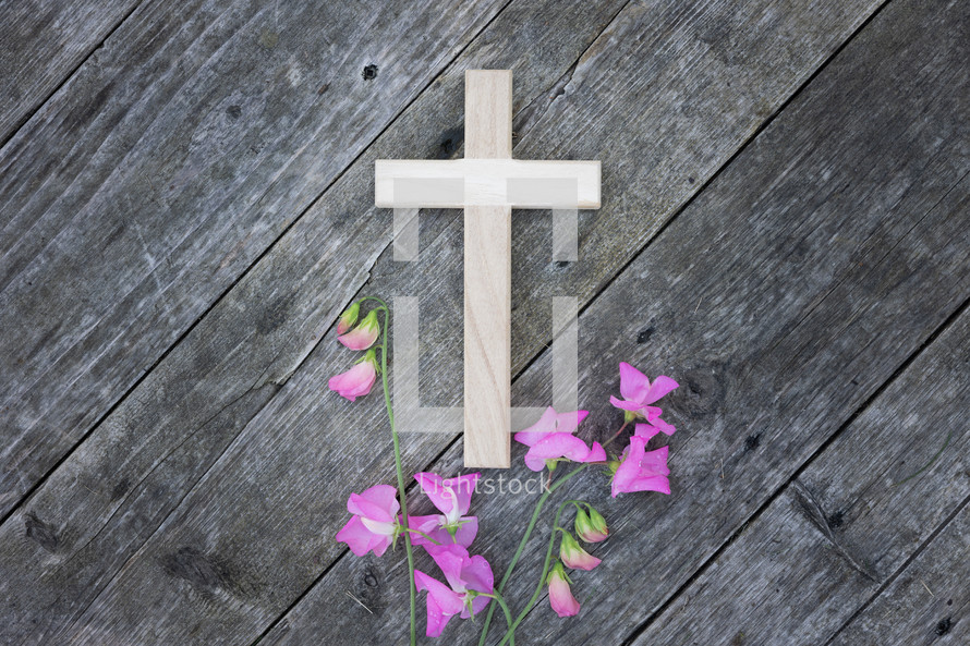 pink flowers and cross on a rustic wood background 