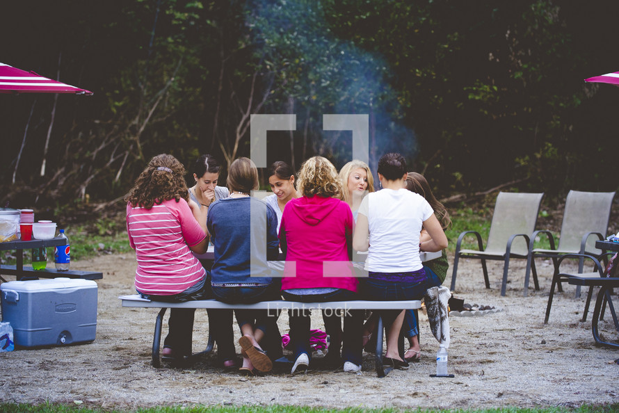 people sitting at a picnic table at a campsite 
