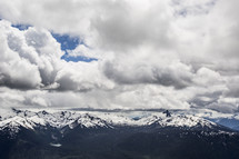 clouds over snow capped mountains 
