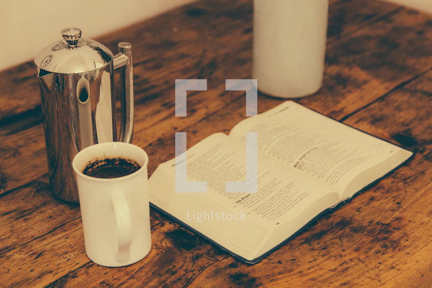 creamer, coffee mug and a Bible on a wood table 