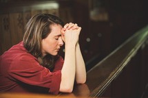 a woman praying alone in a church 