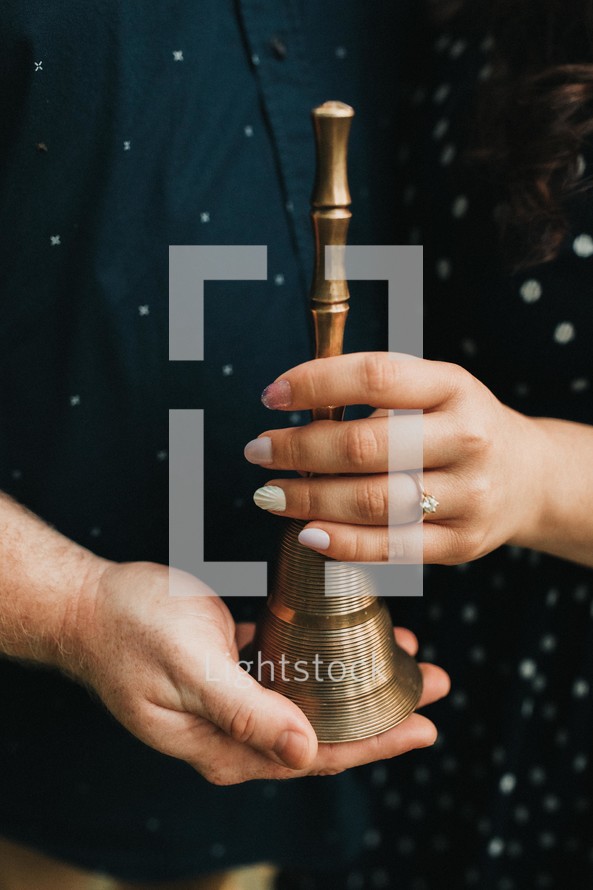 a couple holding a bell 