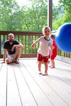 dad and children playing on a deck 