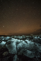 stars in the night sky over and icy shore 