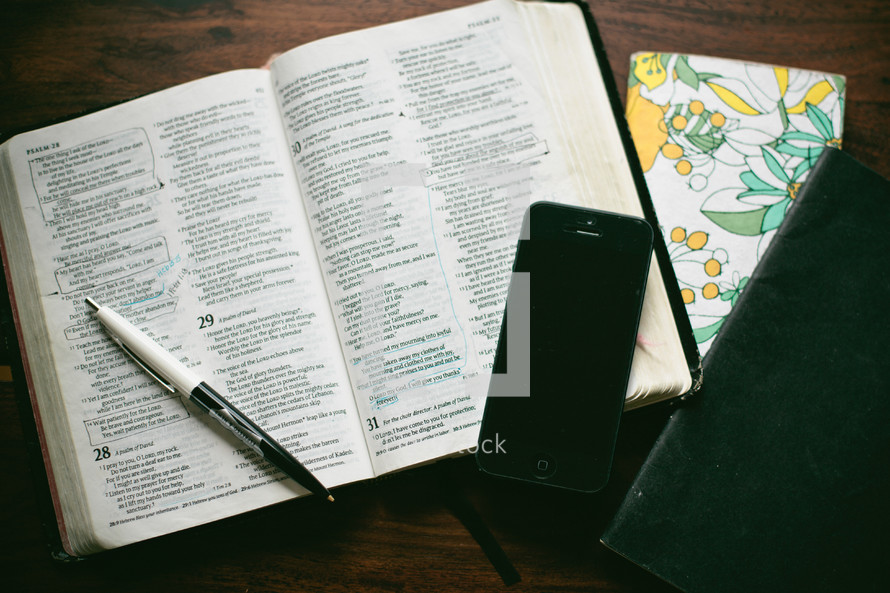 open Bible, cellphone, journal and pen