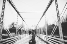 a couple holding each other on a bridge 