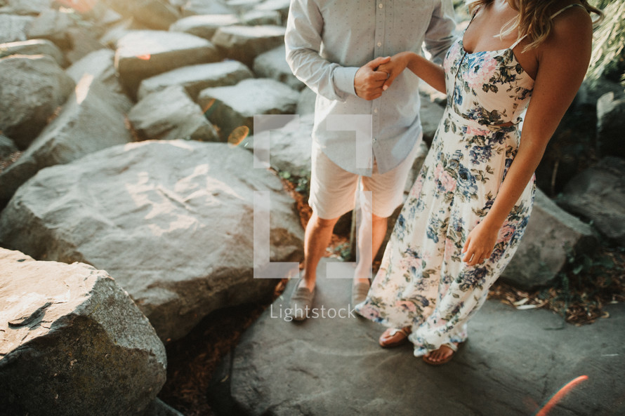 a couple standing on rocks on a beach 