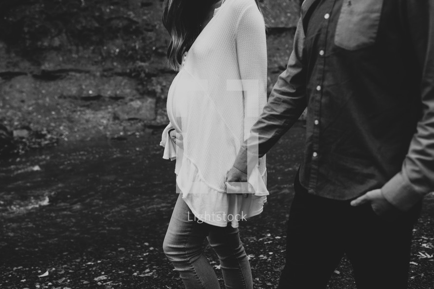 pregnant couple walking holding hands 