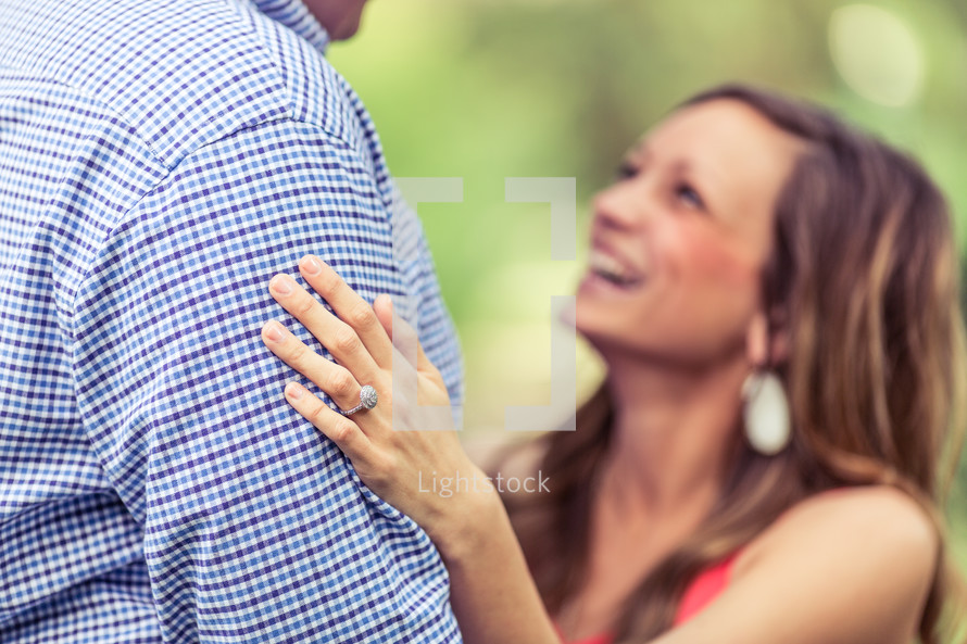 a woman with an engagement ring looking up at her fiancé 