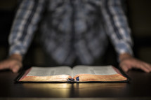 A man standing over an open Bible