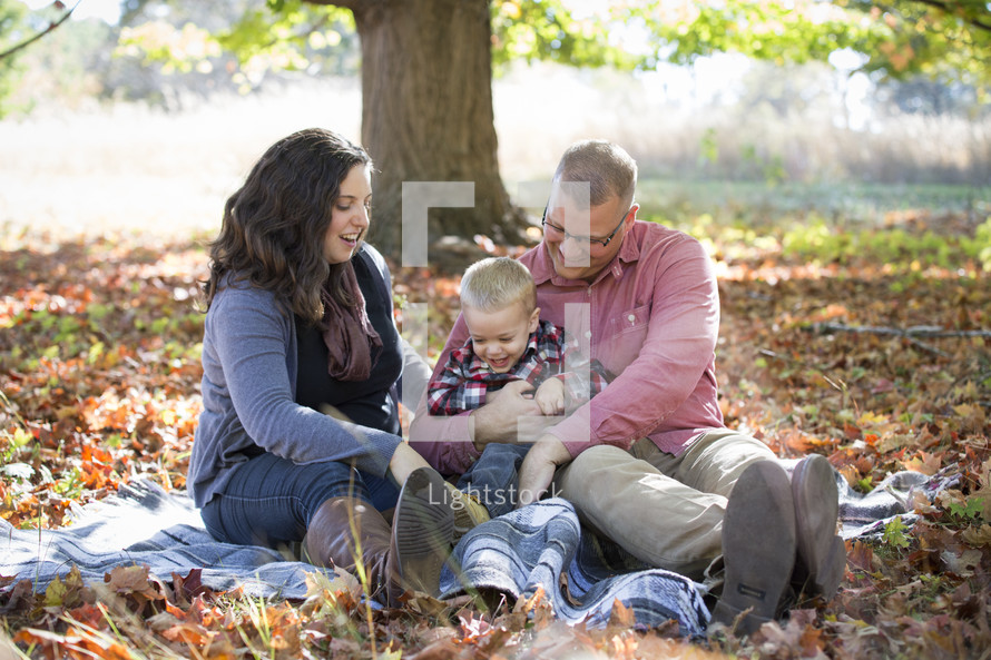 family sitting on a blanket in fall leaves 