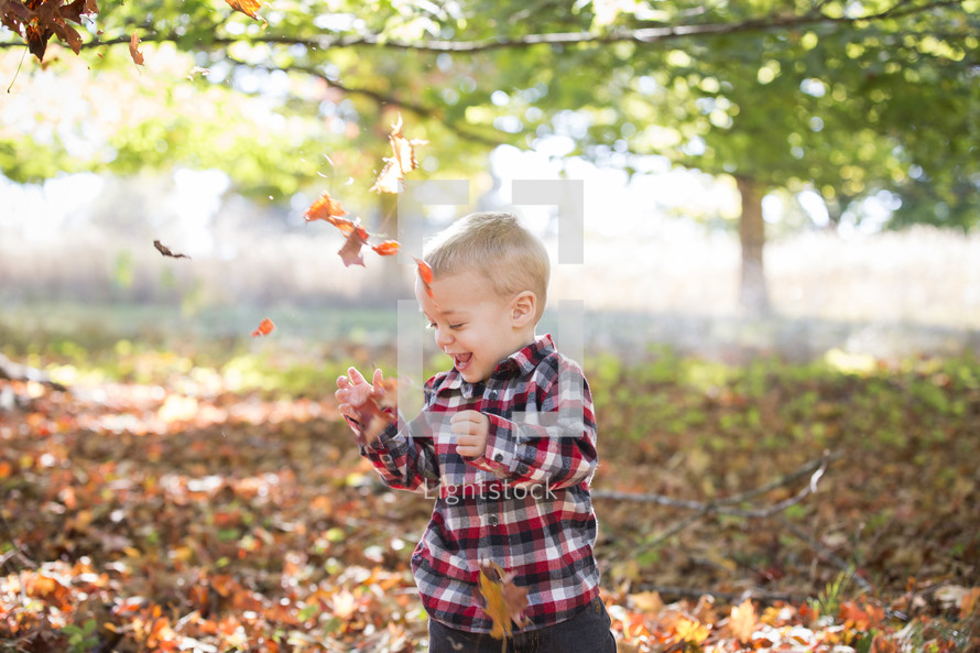 laughing child playing in leaves 