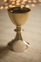 bokeh lights behind a chalice and host