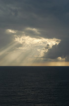Sun beaming through clouds onto ocean