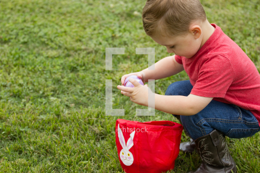 a toddler putting Easter eggs in a basket 