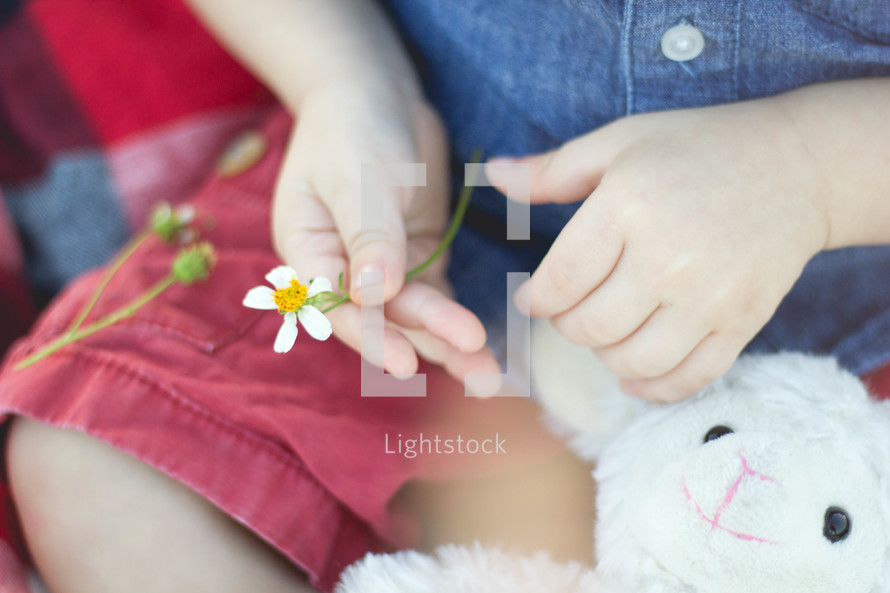 a toddler holding his stuffed animal and a flower 